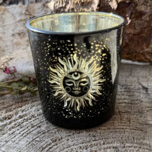Sort fyrfadsstage i glas med gylden inderside og solmotiv omgivet af små stjerner.