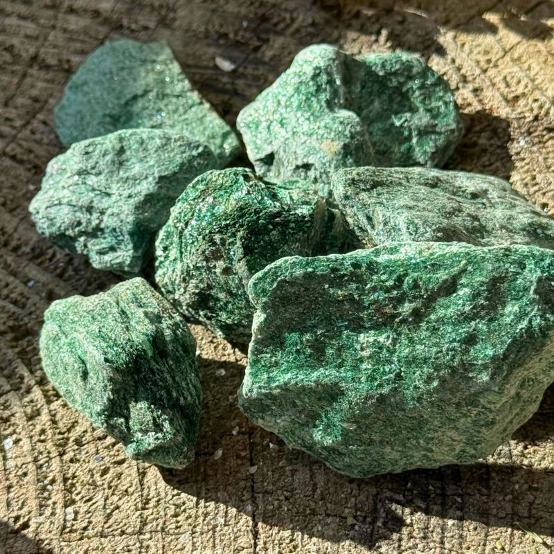 Rå grønne Fuchit krystaller med glitrende mineralflader på træplade